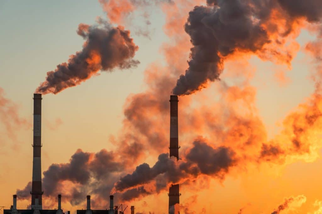fumées sortant de cheminées industrielles dans un soleil couchant